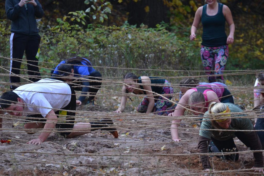 Photo by Lindsey Eaton: Participants crawl through mud and sand while navigating underneath a tangled web of ropes on Saturday, Oct. 21 at the “Muck it U.P.” mud run 5K obstacle course on Marquette Mountain.