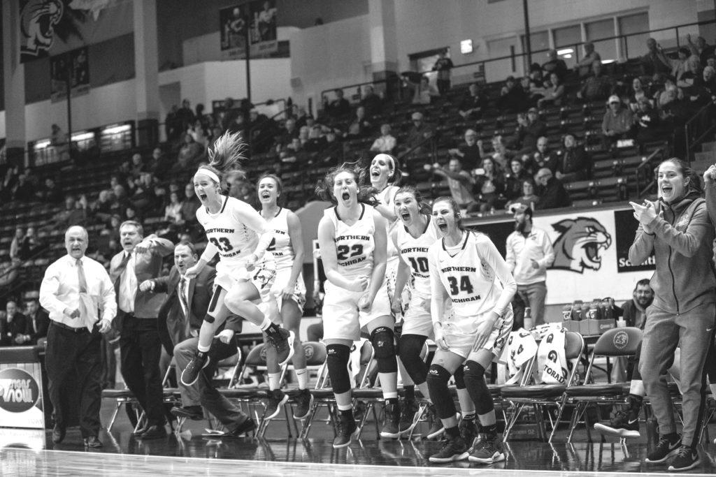 NMU players on the bench jump up in excitement after converting a key basket against Davenport University.
Photo courtesy of NMU Athletics
