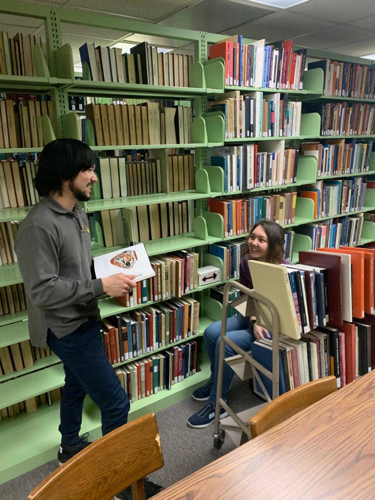 Student library workers, Solomon Gomez, sophomore history major and freshman art and design major AK Ikzoe work on shifting, which is a process to create more space after books are removed from the collection.
Photo by Sophie Hillmeyer
