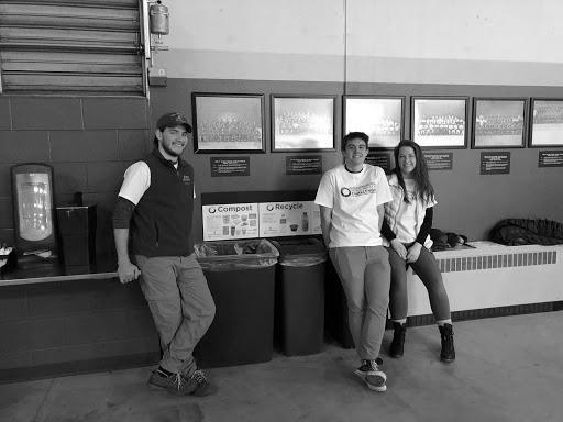 Volunteer Dylan Gonda—a recent NMU graduate—and perspective EcoRep and environmental science major Andrew Jessen sit with elementary major and EcoRep Maggie Pung at a sorting station at the Zero-Waste Challenge hockey game. 
