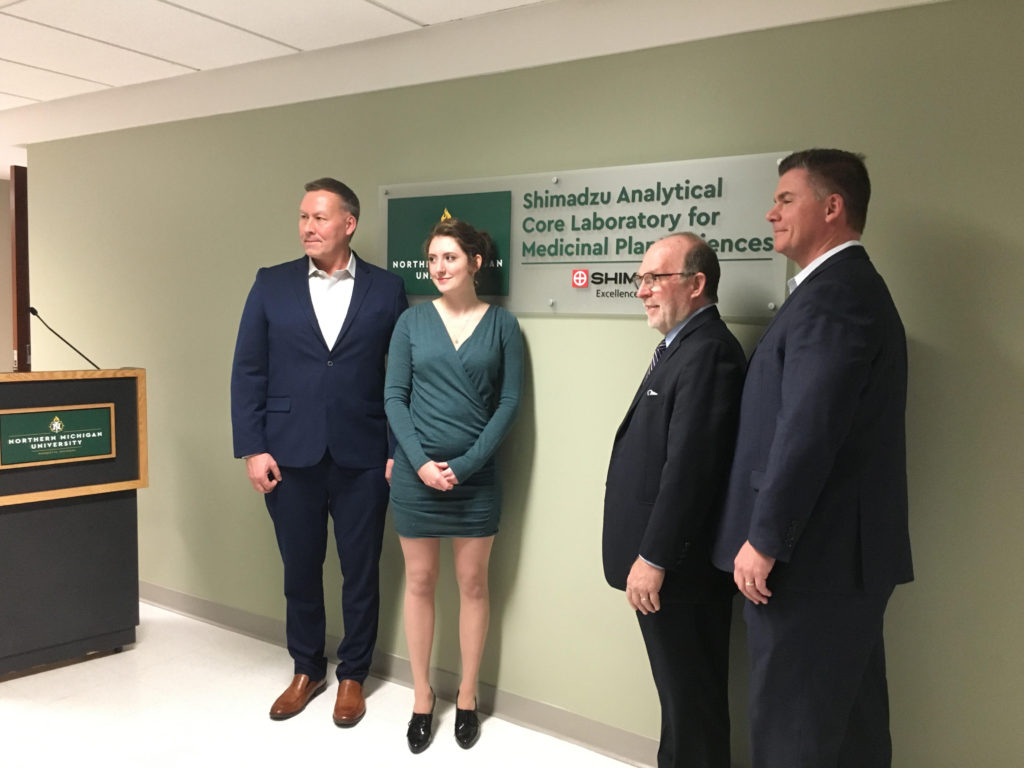 EXCELLENCE UNVEILED—Shimadzu company representatives pose with NMU President Fritz Erickson and Senior chemistry major Josie Mollohan before the newly unveiled plaque before the research laboratory.