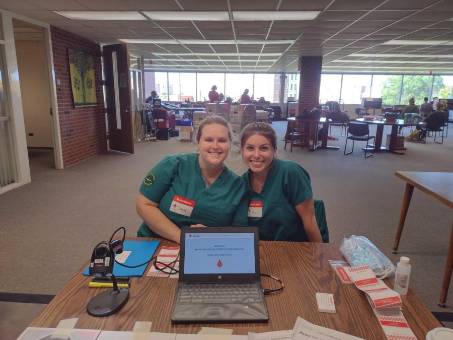 LETS DONATE - Cassidy Orr (left) and Maci Aho (right), seniors and nursing majors, volunteered to work at the registration station at the Red Cross Blood Drive while students, staff, and Marquette community members donate in the background. 
