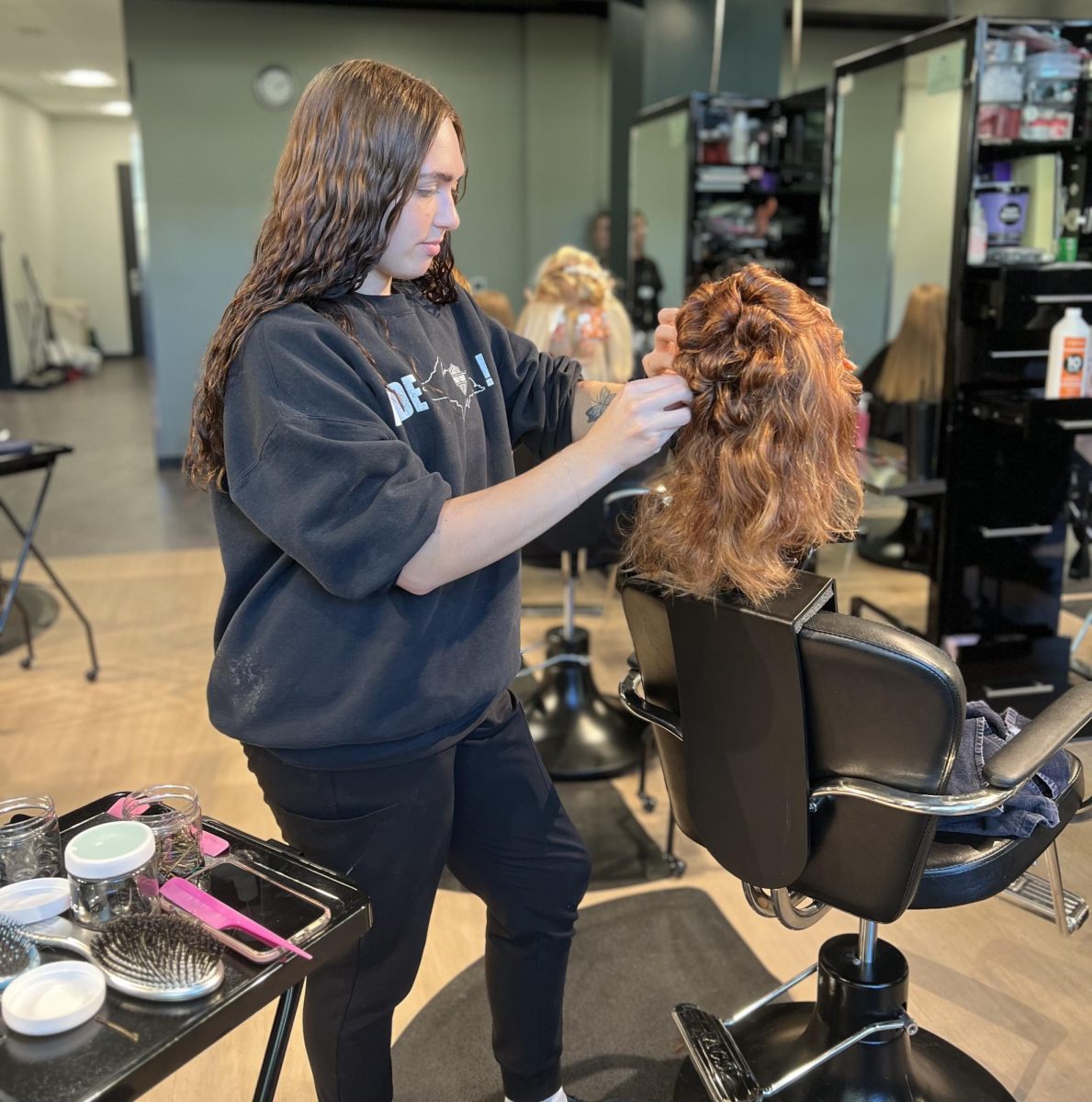 TALENTED STYLING — With steady hands, a student focuses as she works on an intricate hairstyle.