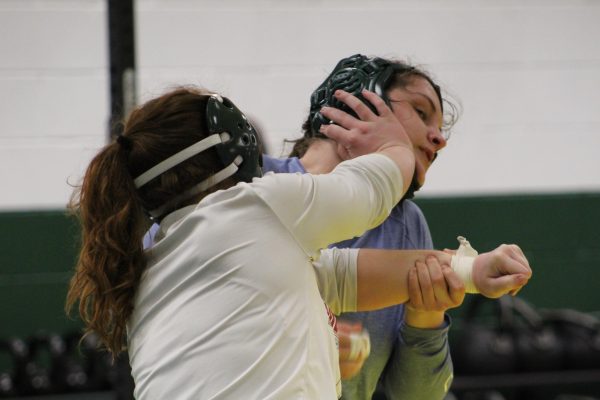 TAKING A HIT — Two athletes on the NMU Womens Wrestling team grapple during practice. 