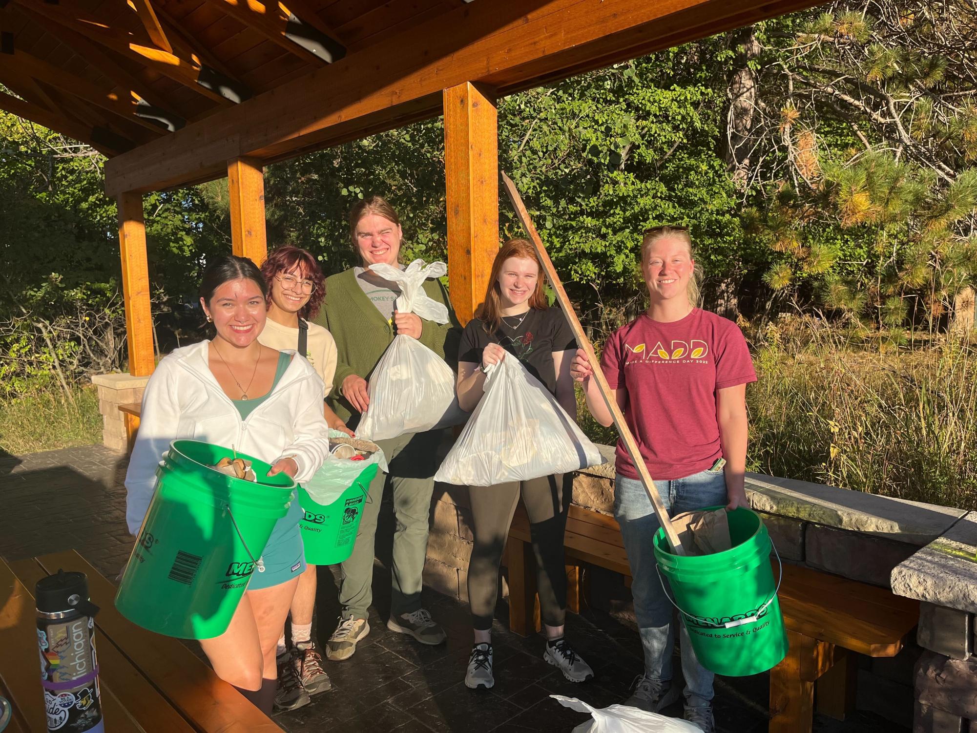 CLEAN UP - NMU Conservation Crew members Anna Tousley, Korina Benavidez and Taylor Kenyon, along with volunteers, display the loads of trash found on campus at their latest clean-up event. 