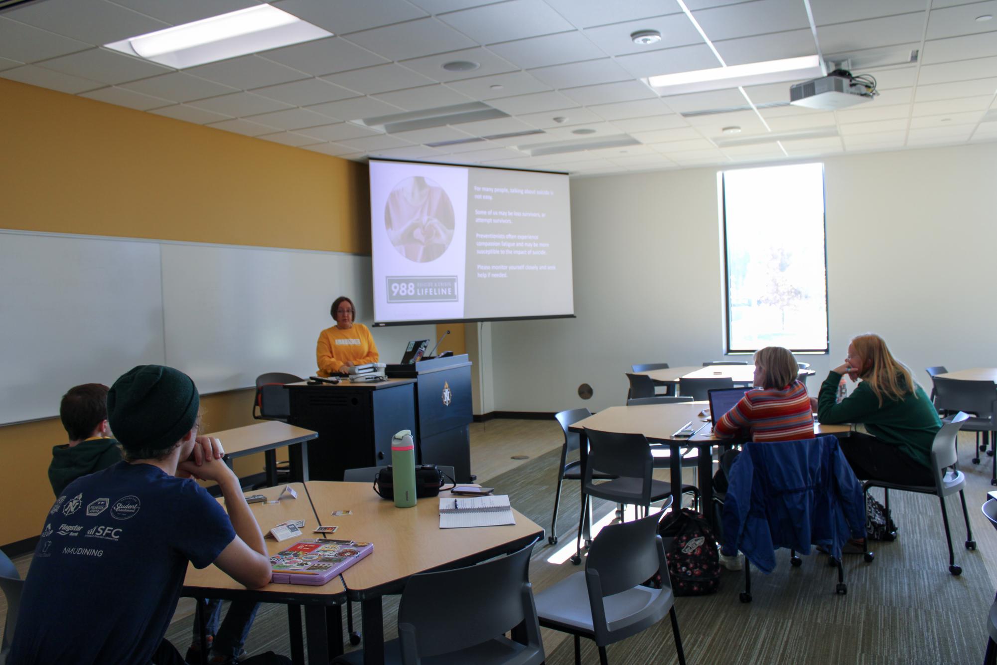 QUESTION, PERSADE, REFER - Amy Poirier presents the National Suicide Prevention Hotline onscreen as a resource for students struggling with mental health issues and suicidal ideations. 