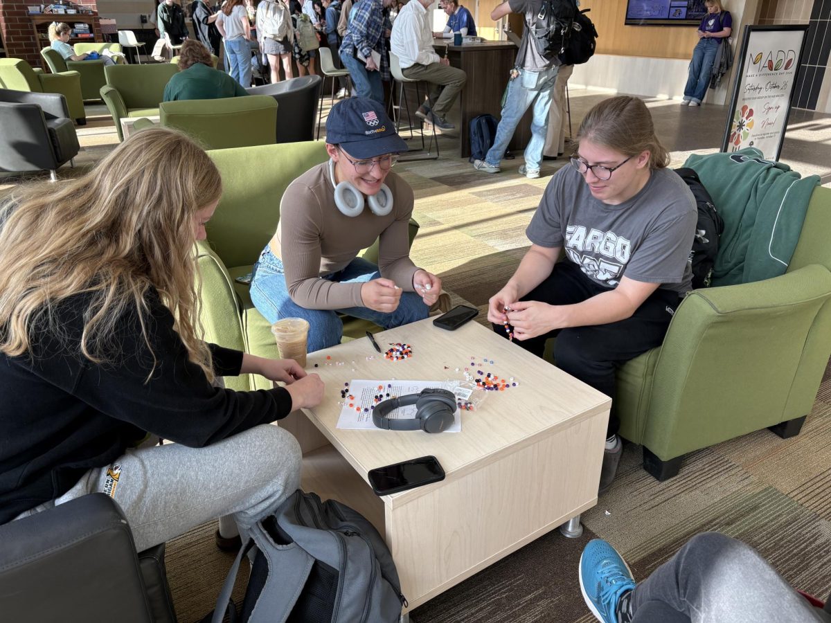 CREATE- A group of girls carefully choose charms to put on their bracelets in Jamrich lobby. 