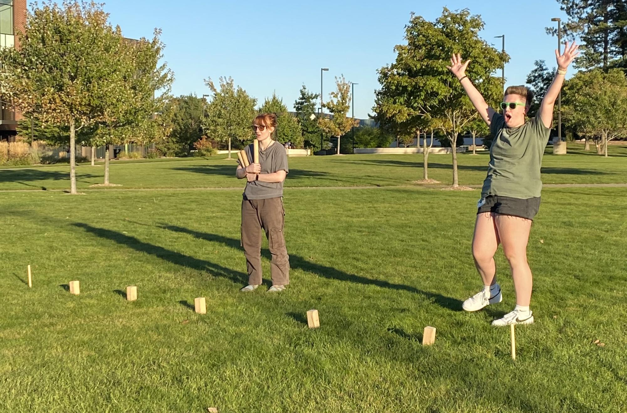 TEAMWORK- RA Kaitlyn Straschinske and her teammate, freshman Christine Corner, celebrate after knocking down a "kubb," bringing them one step closer to winning the game of the same name. 