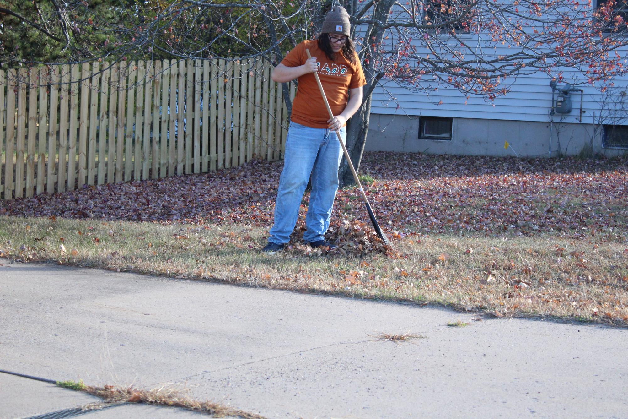 RAKE IT UP - An NMU student rakes leaves at a community member's home, making a difference one leaf at a time. 