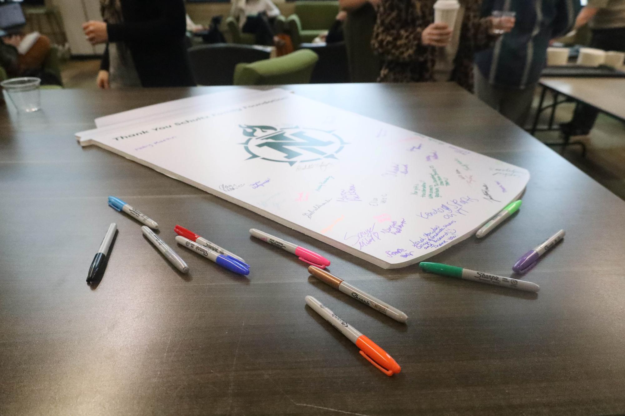 THANKS HOWARD — Students sign a large Starbucks coffee cup to give their thanks back to Schultz for his donation to the university. 