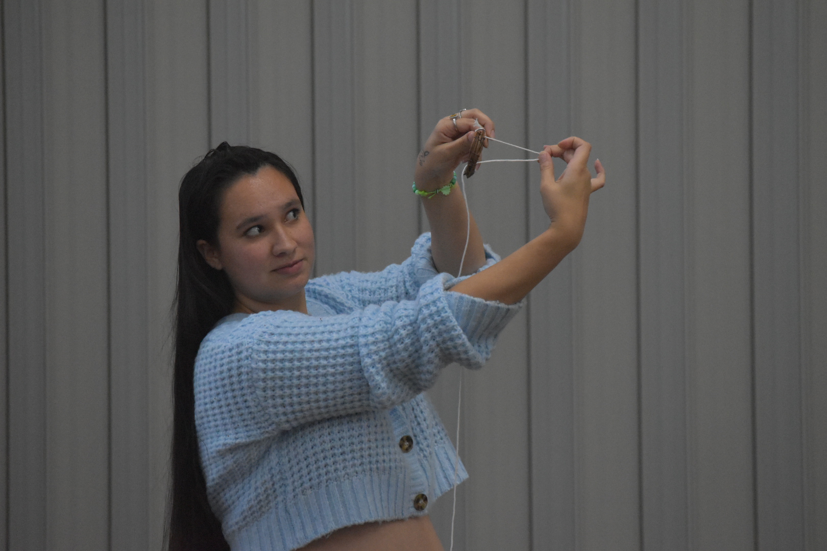 STOP AND LOOK — Students are shown how to weave string through their dreamcatcher.